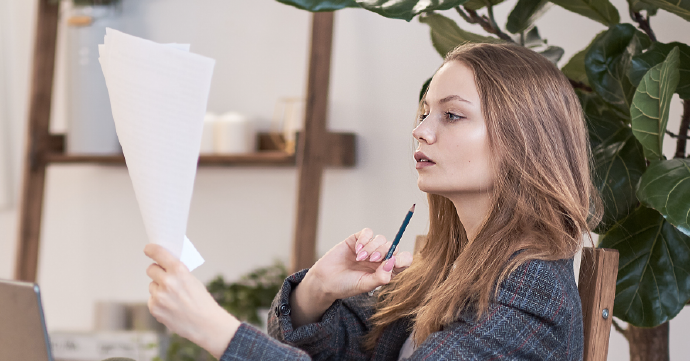 Multiple Pages of a Document Being Arranged Person holding paper and a pencil.