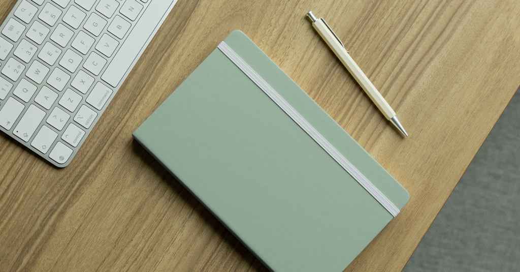 Hardback Notebook A hardback notebook and pen on a desk.